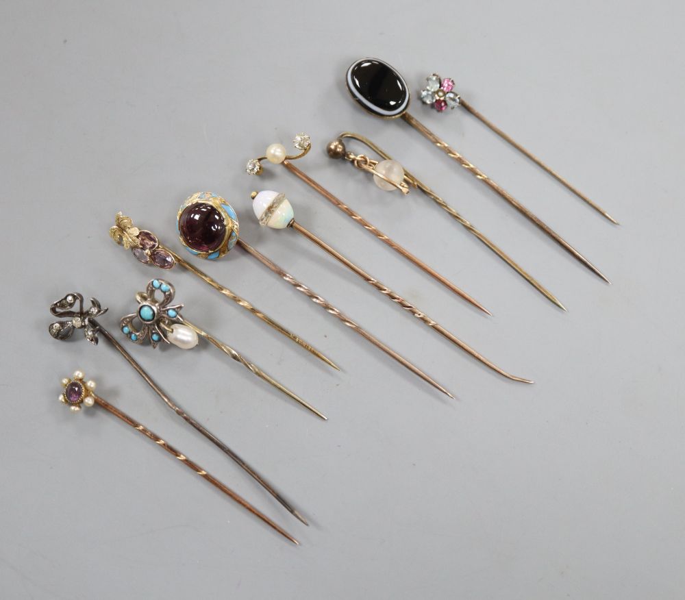 Ten assorted 19th century and later yellow metal and gem set stick pins, including garnet and enamel and banded agate,